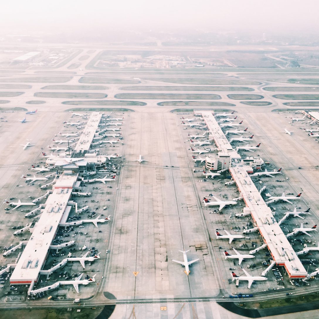 Aerial view of planes docked at two airport terminals.