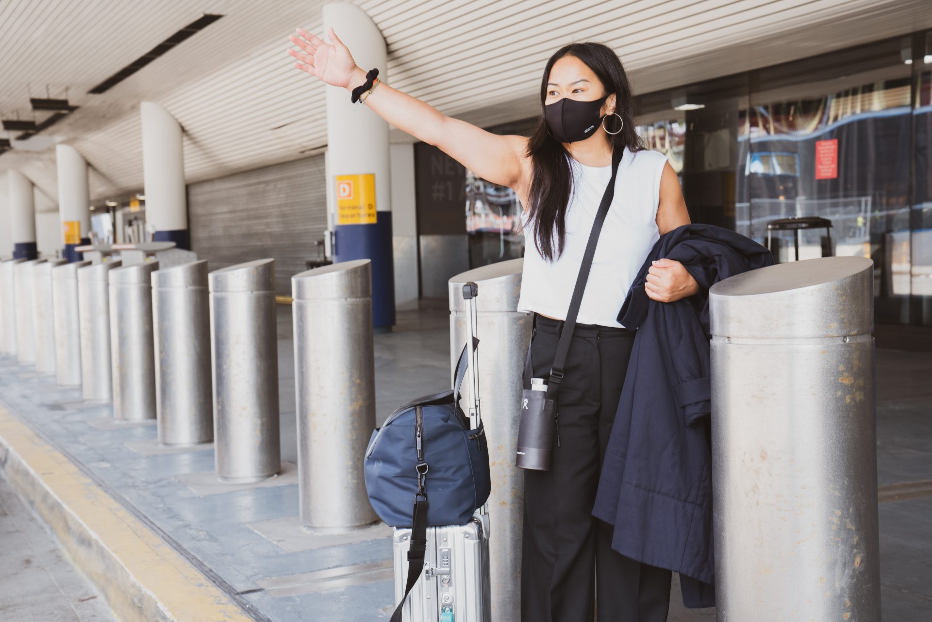 Woman waving at someone outside an airport.