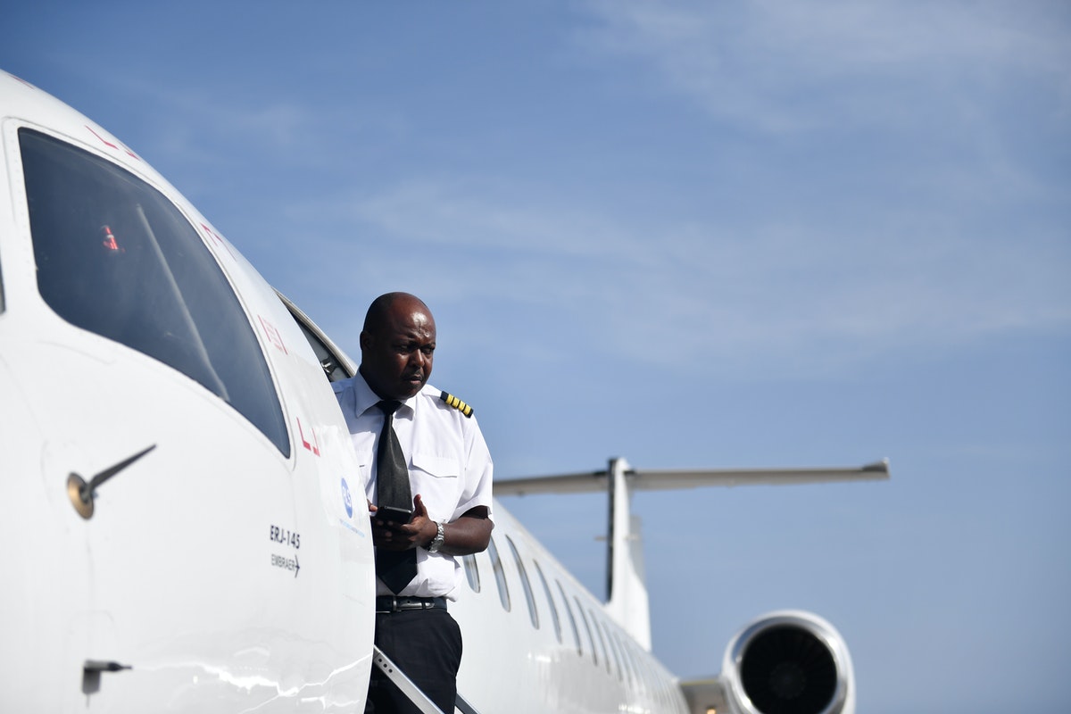 Pilot stands at the door of an airplane.