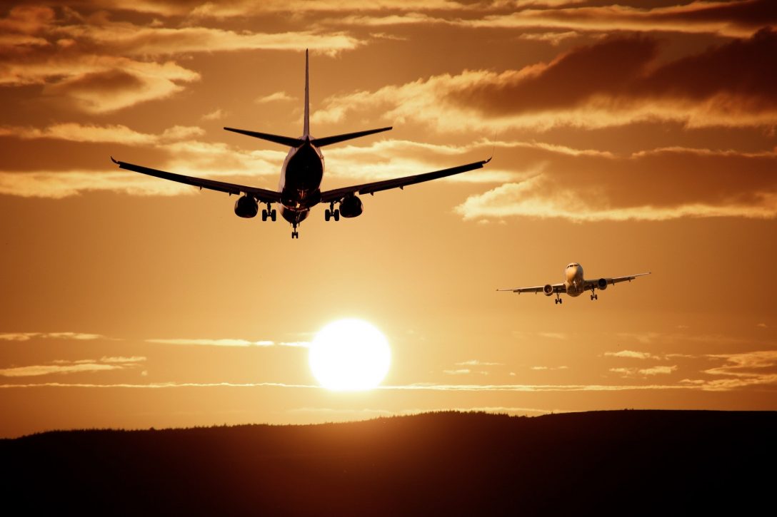 Two airplanes taking off and landing at sunset.